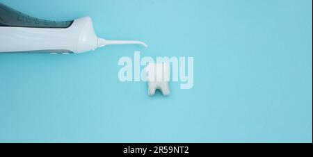 Irrigator near tooth model on blue background, professional clean teeth, teeth will good healthy. Dentist tools. Teethcare, dental health concept. Mea Stock Photo