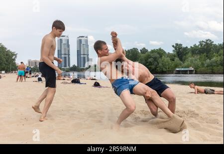 KYIV, UKRAINE - May. 27, 2023: Teenagers relax and have fun in beach wrestling on the city beach in Kiev despite the daily missile attacks on the Ukrainian capital. Stock Photo