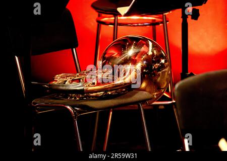 The image of a wind brass musical instrument horn lies on a chair in the theater Stock Photo