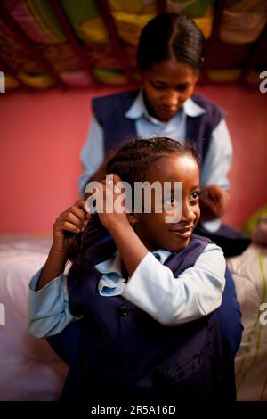 Ethiopian girls braid hair before school at the Artists For Charity Home, Addis Ababa, Ethiopia. Stock Photo