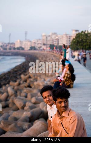 Indians enjoy the setting sun over the Arabian Sea along the waterfront of Marine Drive in Mumbai, India. Stock Photo