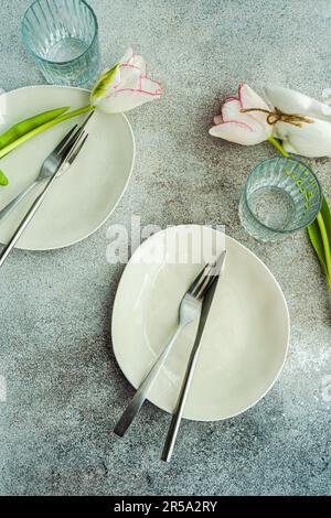 Table setting with seasonal flowers on concrete background Stock Photo