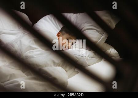 Sleepy boy is lying in bed under a blanket in the bedroom Stock Photo