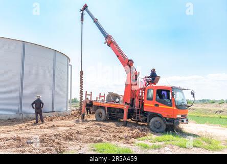 Mobile pile driver drill pit for pole foundation support silo tank in construction site. Stock Photo