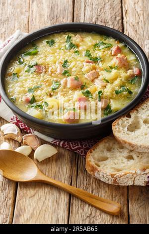 Soup kulesh with millet, potatoes and bacon in a black bowl on a wooden table closeup. Vertical Stock Photo