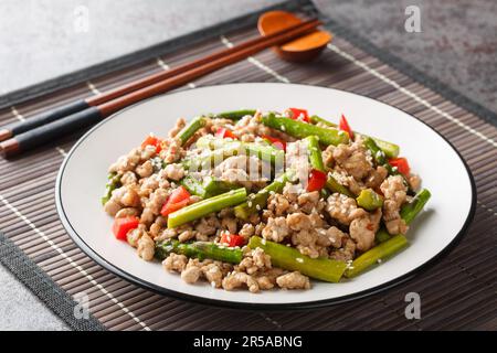 Asian Stir Fry minced pork with asparagus, garlic, chili, soy sauce and sesame close-up in a plate on the table. Horizontal Stock Photo