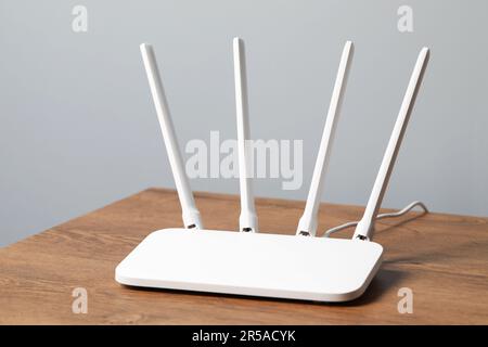 New white Wi-Fi router on wooden table indoors Stock Photo