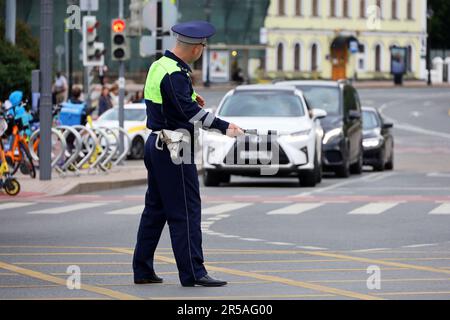 Traffic police officer standing with rod on a road on cars background. Policeman patrol the city street Stock Photo