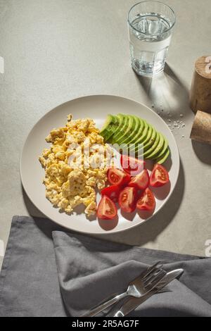 scrambled eggs with avocado and tomatoes in a gray plate Stock Photo