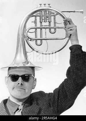 In the 1950s. A man with a brass horn musical instrument on his head. Sweden 1956 Stock Photo