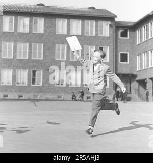 The last school day. The boy jumps happily on his last school day for the term, holding his grade paper in the hand. Well dressed as children were in the 1950s decade. Sweden 1950s. ref BV40-11 Stock Photo