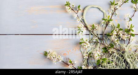 Shopping mesh string bag green with cherry blossom branches on a wooden blue background with a place for your text. Flat lay, top view. Zero waste and Stock Photo