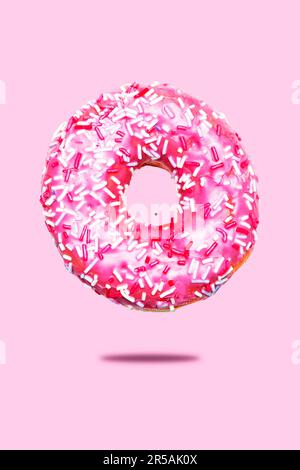 Donut with pink glaze and sprinkles. Isolated on a pink background. Stock Photo