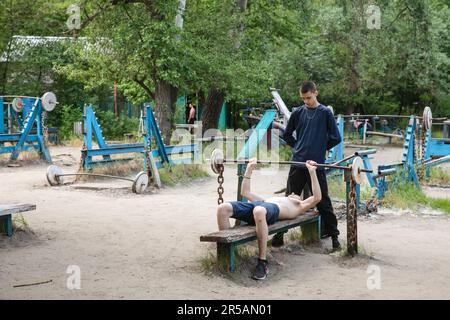 KYIV, UKRAINE - May. 27, 2023: Teenagers are seen doing strength training  in soviet-era outdoor gym Kachalka in a Kyiv park, Ukraine Stock Photo