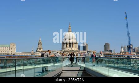 London, UK - 14 May 2022. Pedestrians walking across Millennium Bridge with St.Paul's Cathedral in the background. Blue skies. Stock Photo