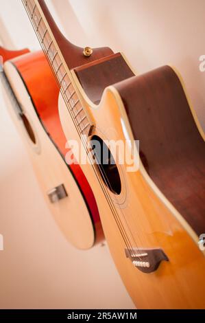 Two classic acoustic guitars hanging on the wall. Classic vintage acoustic guitars. Instruments made of wood. Stock Photo