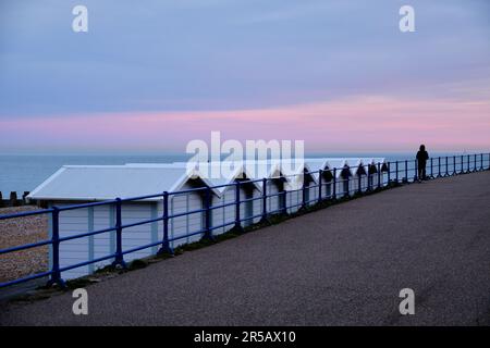 Eastbourne, UK. April 14, 2022. Row of beach huts leading to isolated person. Stock Photo