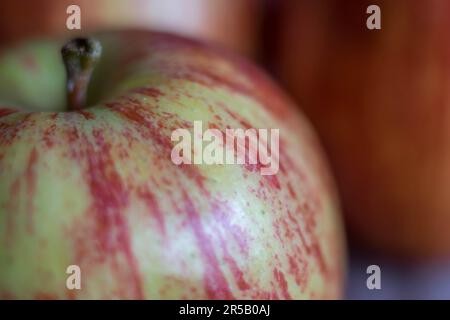 A ripe red apple with a portion missing sitting on a white background next to an intact yellow fruit Stock Photo