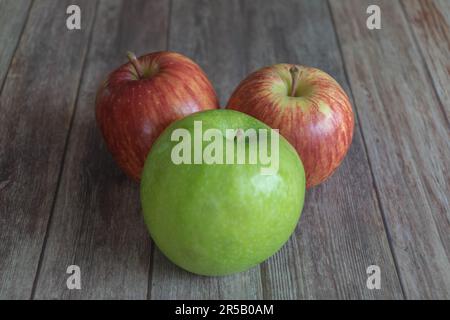 The two red and one green apple on a wooden table Stock Photo