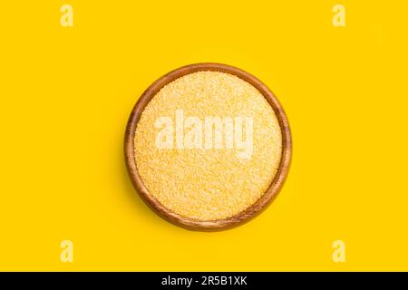 Cornmeal in a wooden bowl on a yellow background in a top view Stock Photo