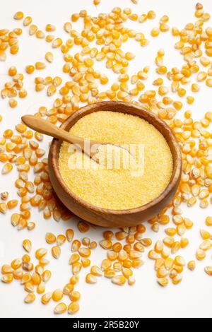 Cornmeal in a wooden bowl and corn kernels on a white background in a top view Stock Photo