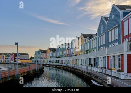 Row of colourful wooden newly built Dutch houses surrounded by water of lake De Rietplas in Houten in the Netherlands. Stock Photo