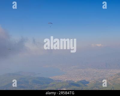 Paragliding in sky. Paraglider tandem flying over sea and mountains in cloudy day. view of paraglider and Blue Lagoon in Oludeniz, Turkey. Extreme sport. Landscape Stock Photo