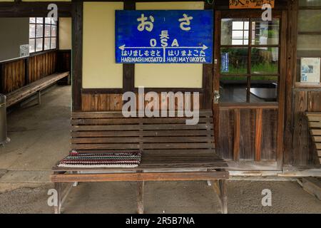 Hyogo, Japan - May 15, 2023: Empty bench and waiting room with sign for Osa Station in rural area Stock Photo