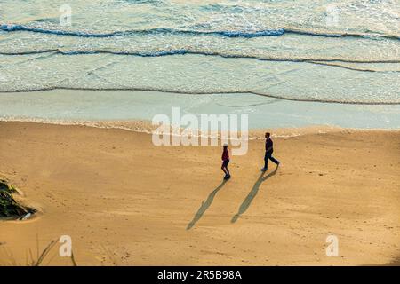 Young couple walking at sunset on the beach at Whitesands Bay, a Blue Flag beach, St David's peninsula, Pembrokeshire Coast National Park, West Wales Stock Photo