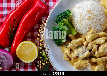 A wholesome, balanced meal of grilled chicken and seasoned rice with steamed vegetables on the side, served on a white ceramic plate Stock Photo