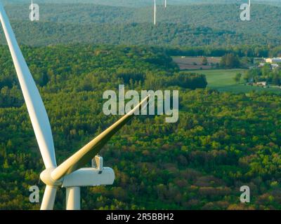 Afternoon aerial drone view of wind power turbines under construction, on a green forest. Wind turbines are part of the energy transition strategy Stock Photo