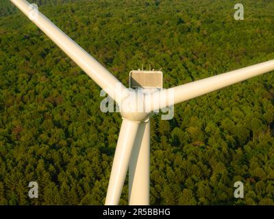 Afternoon aerial drone view of wind power turbines under construction, on a green forest. Wind turbines are part of the energy transition strategy Stock Photo