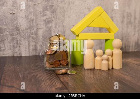 Wooden figurines of a family near a white house. The concept of a housing loan for a young large family Stock Photo