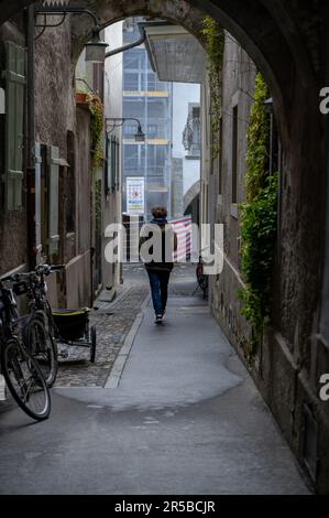 A young adult is navigating their way through a narrow passageway lined with bicycles and other two-wheeled vehicles Stock Photo