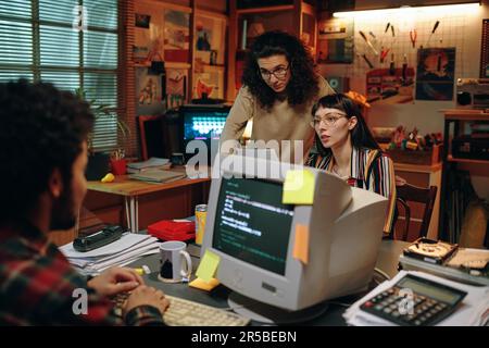 Group of young people discussing new project together, they working on computer in garage Stock Photo