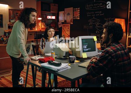 Group of young people working over new project at table with computers in garage Stock Photo