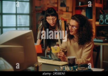 Young people using floppy disk to save information from computer during their teamwork in garage Stock Photo