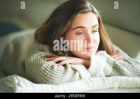 Young girl lying on couch, looking nowhere, sad emotions Stock Photo