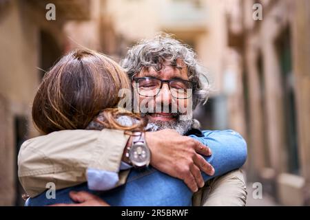 Close up portrait of happy older gray-haired man embracing adult woman outdoor.  Stock Photo