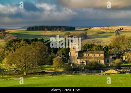 Beautiful old stone church view (rural Dales village, evening light & sunlight on land & fields, upland moors) - Rylstone, North Yorkshire, England UK Stock Photo