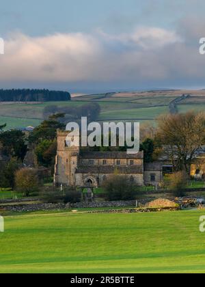 Beautiful old stone church view (rural Dales village, evening light & sunlight on land & fields, upland moors) - Rylstone, North Yorkshire, England UK Stock Photo