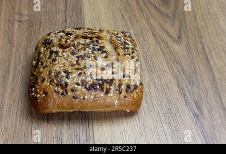 close-up of  bun with sesame seeds, sunflower and grains on wooden table Stock Photo