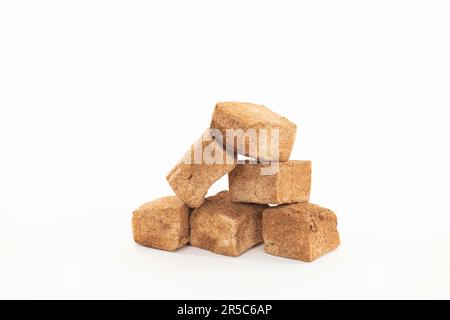 Three cubes of unrefined brown sugar stacked on top of each other on a plain white background Stock Photo