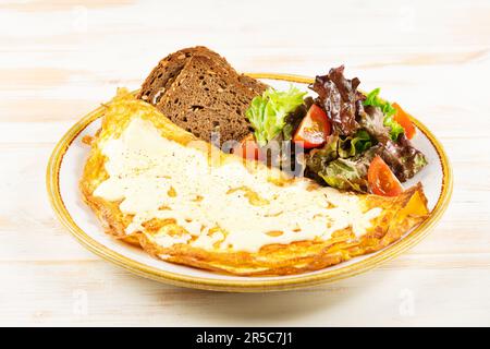 Omelette with cheese, tomatoes and green on wooden background. Tasty breakfast. Stock Photo
