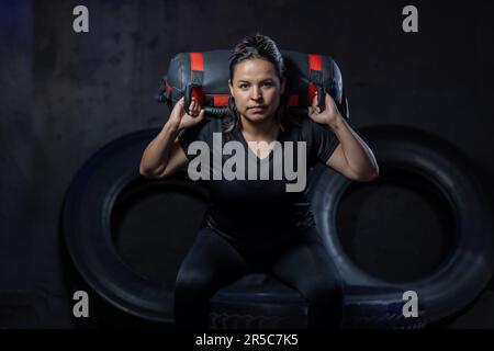 A young woman wearing a black top and denim jeans confidently holds a wheel cushion in her hands Stock Photo