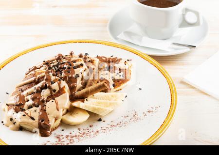 asty dessert made with pancakes, chocolate syrup and cup of coffee on white background. Breakfast concept. Stock Photo