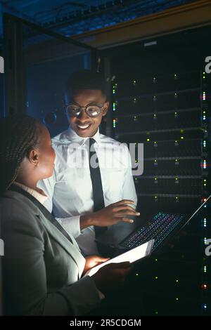 Sharing technical knowledge. two young IT specialists standing in the server room and having a discussion while using a technology. Stock Photo