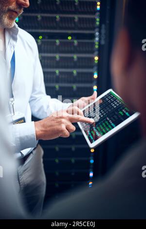 Find the solution, save the day. Closeup shot of an unrecognisable man using a digital tablet while working with a colleague in a server room. Stock Photo