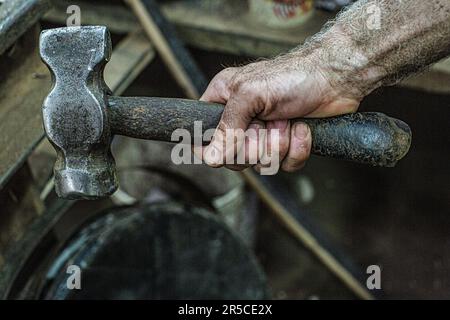 Cooper hand with hammer to work on whisky casks at the Speyside Cooperage in Craigellachie, Scotland Stock Photo