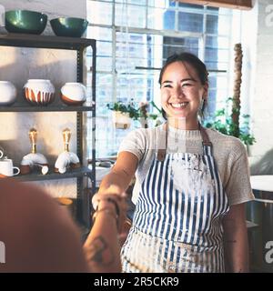 Time to make ceramic magic. two young women shaking hands in a pottery studio. Stock Photo